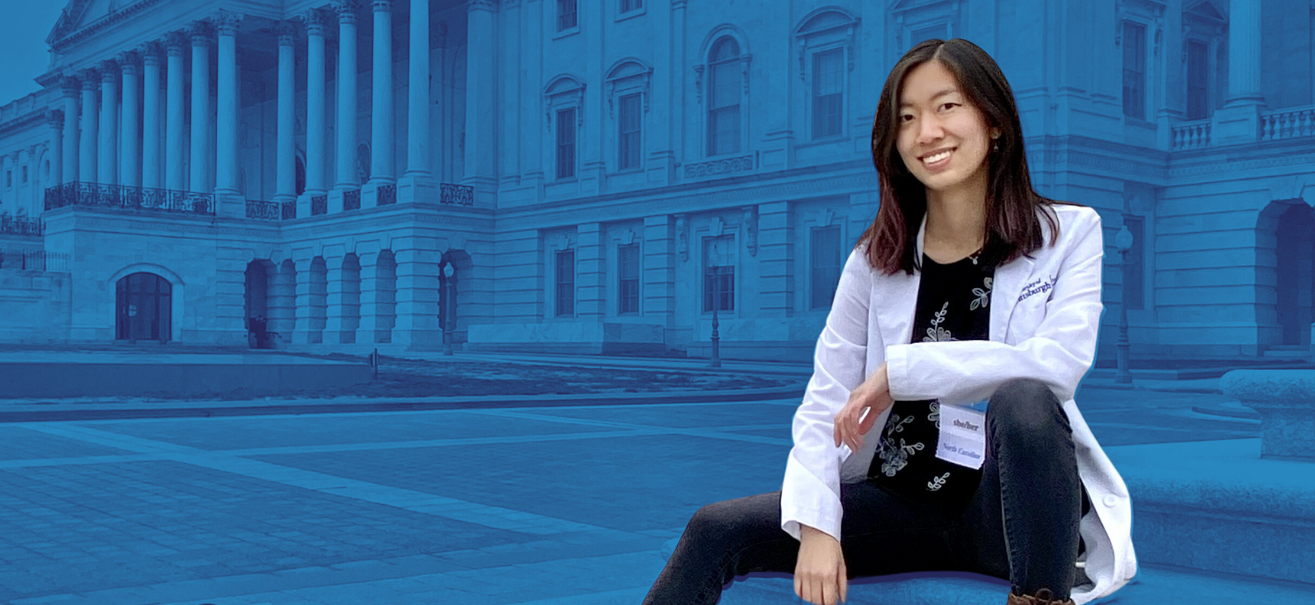 Anna Li sitting on steps outside of a government building wearing her white coat.